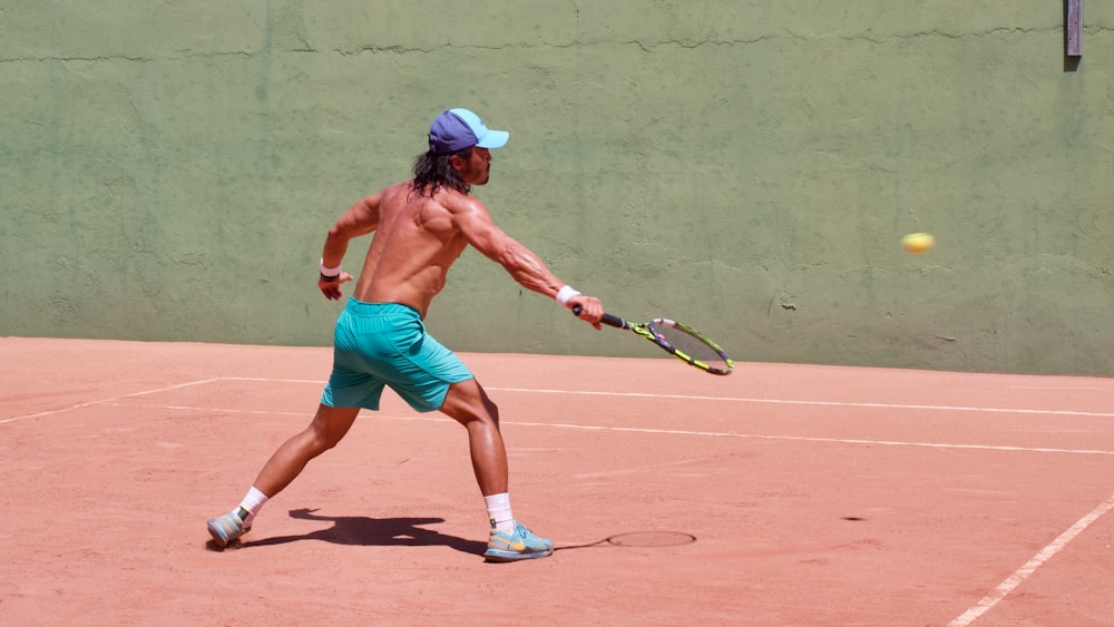 a shirtless man playing tennis on a tennis court