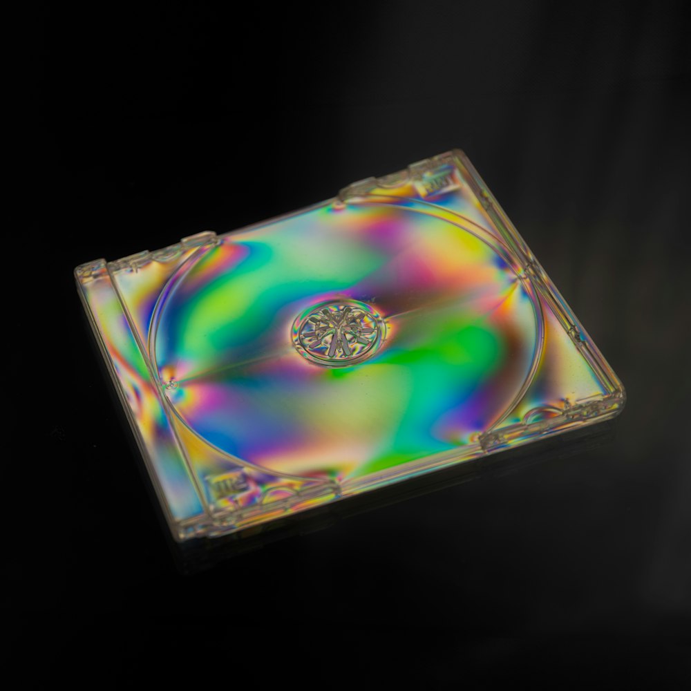 Um CD colorido sentado em cima de uma superfície preta