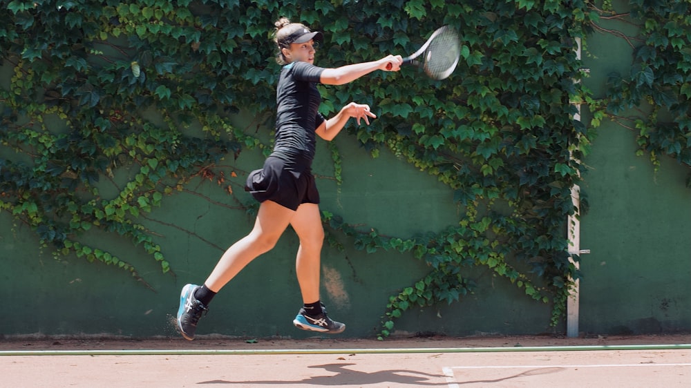 a woman in black shirt and shorts playing a game of tennis