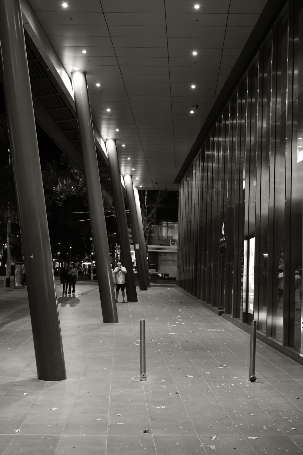 a black and white photo of people walking down a sidewalk