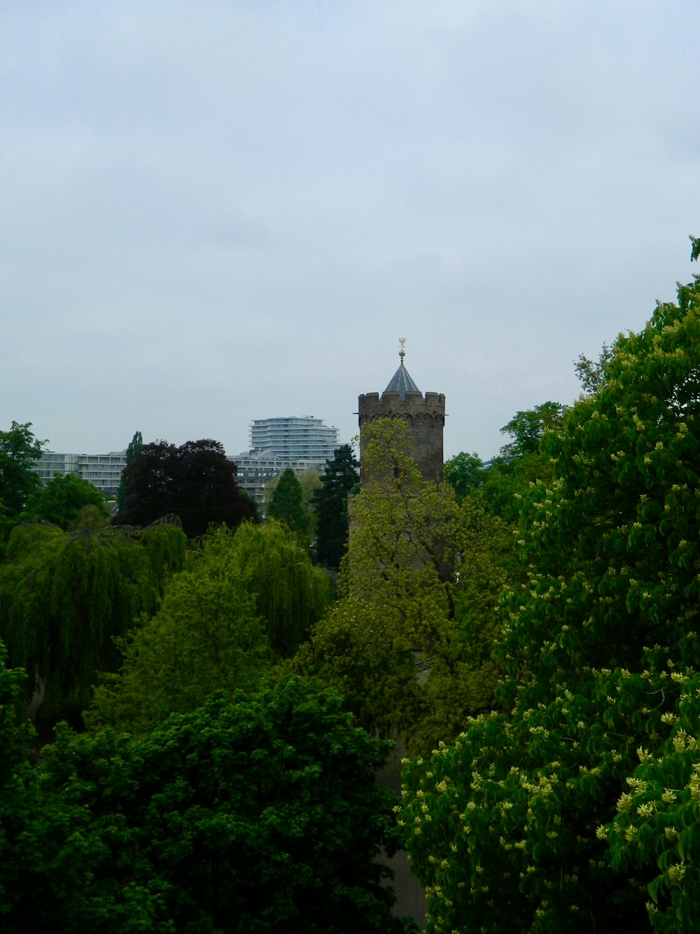 a tower with a cross on top of it surrounded by trees