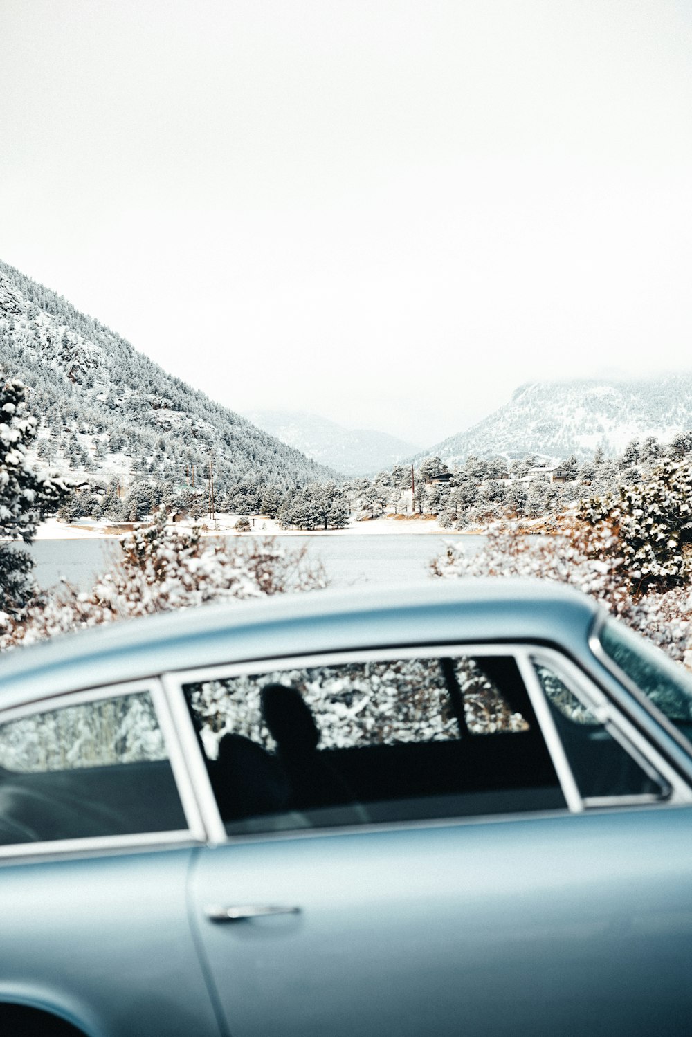 a blue car driving down a snow covered road