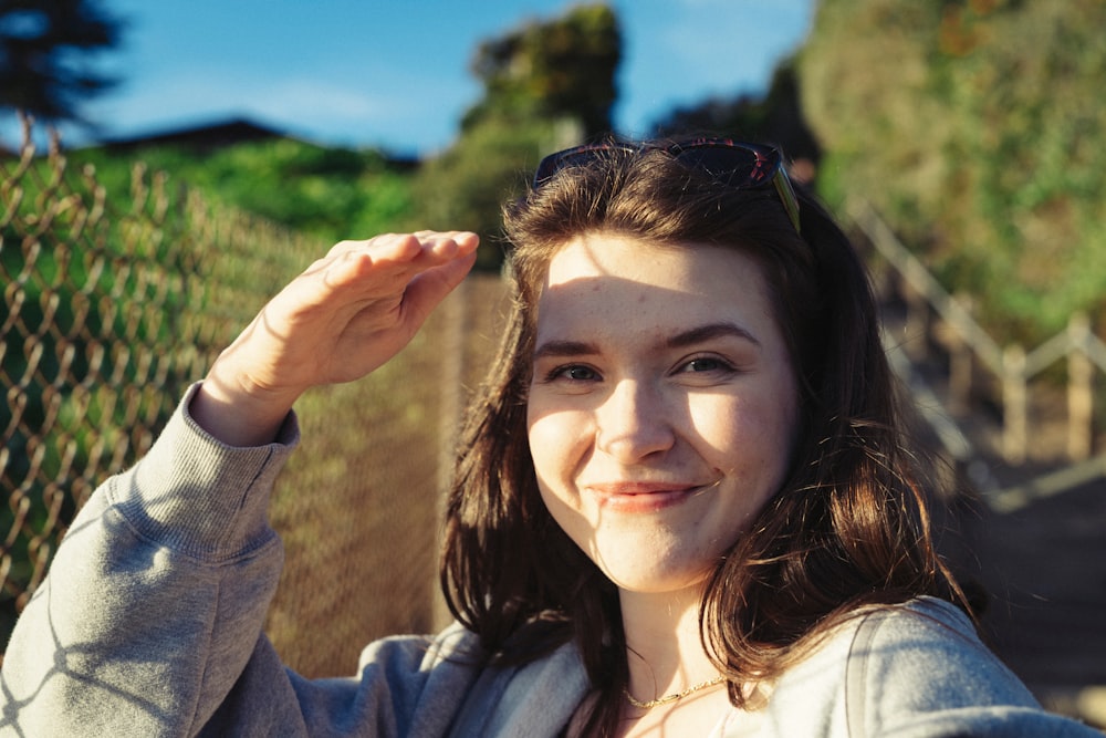 a young woman poses for a picture in front of a chain link fence