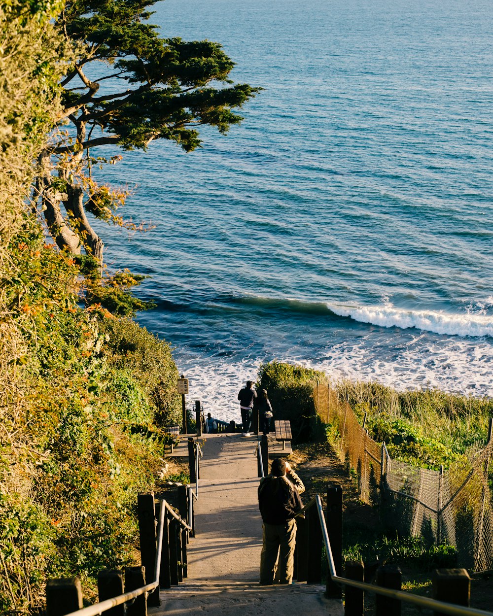 a man walking down a set of stairs next to the ocean