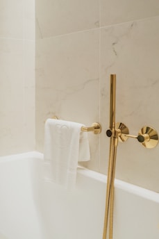 a white bath tub sitting next to a gold faucet