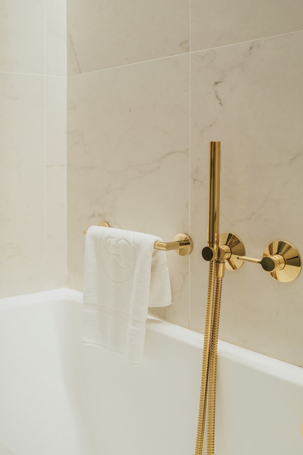 a white bath tub sitting next to a gold faucet
