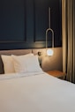 un lit avec des draps blancs et des oreillers dans une chambre