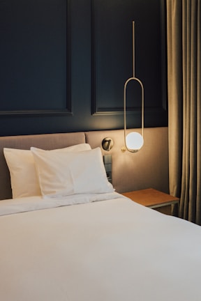 a bed with white sheets and pillows in a room