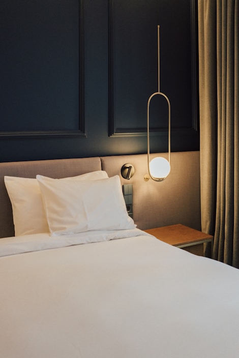 a bed with white sheets and pillows in a room