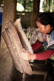 a woman in a red and white striped shirt working on a piece of wood