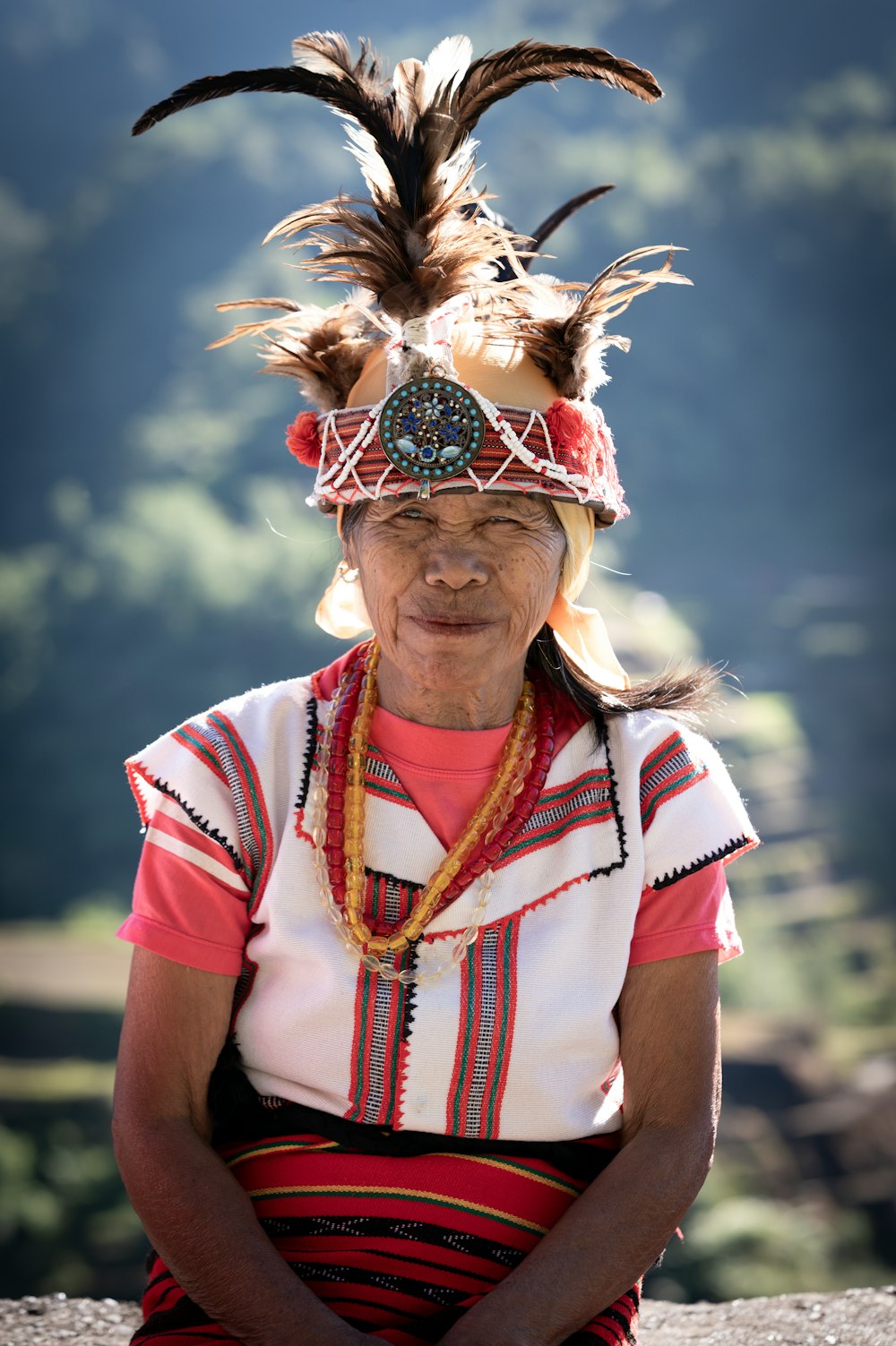 a woman wearing a headdress sitting on a rock