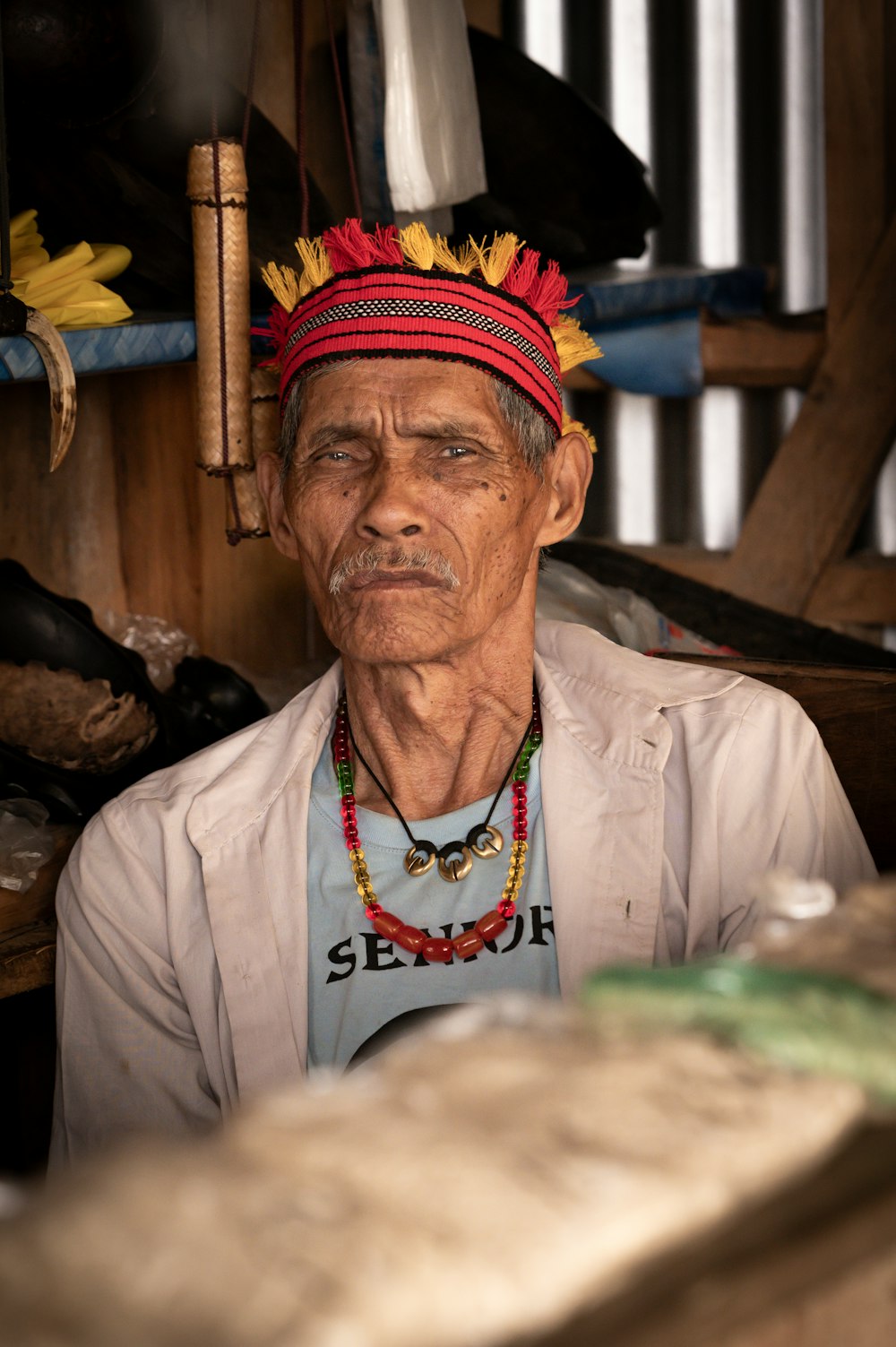 a man wearing a colorful headdress sitting in a room