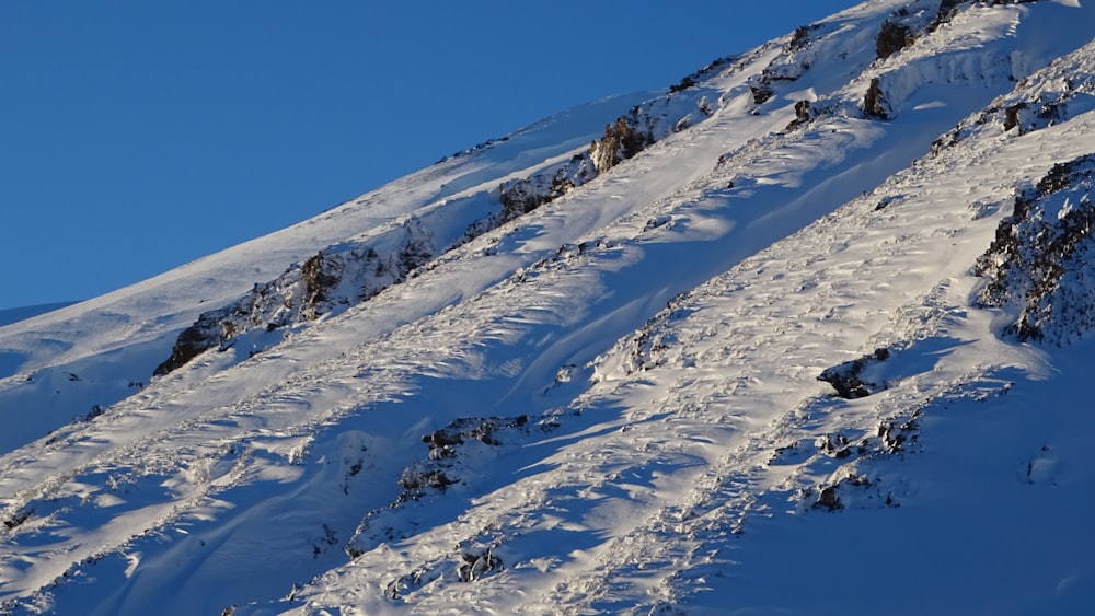 a man riding a snowboard down the side of a snow covered slope