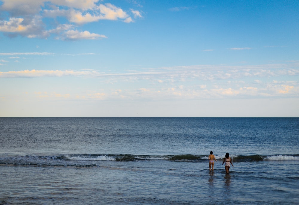 two people standing in the ocean with a kite