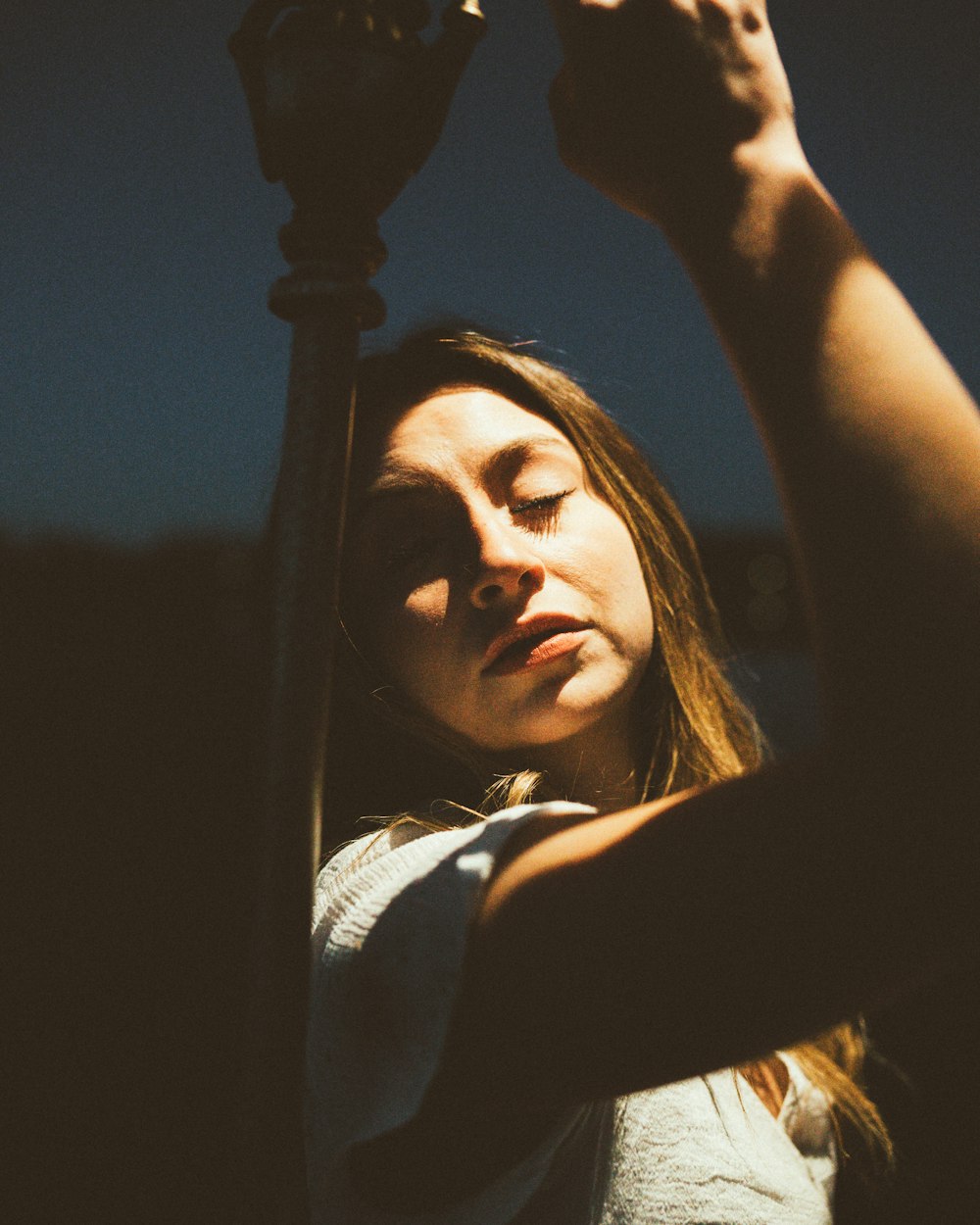 a woman holding a lamp post in her hands