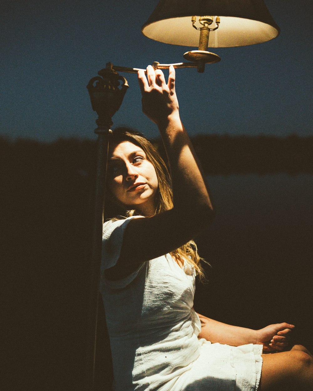 a woman sitting on the ground under a lamp