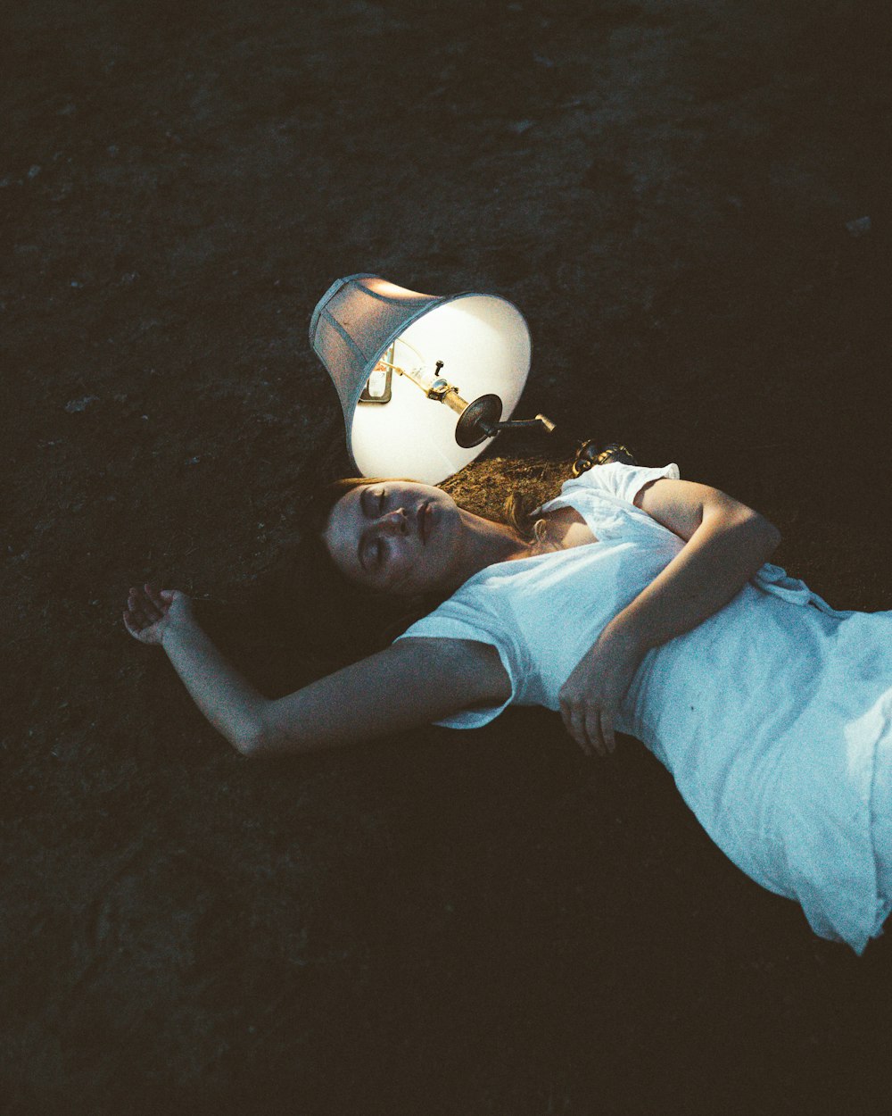 a woman laying on the ground next to a lamp