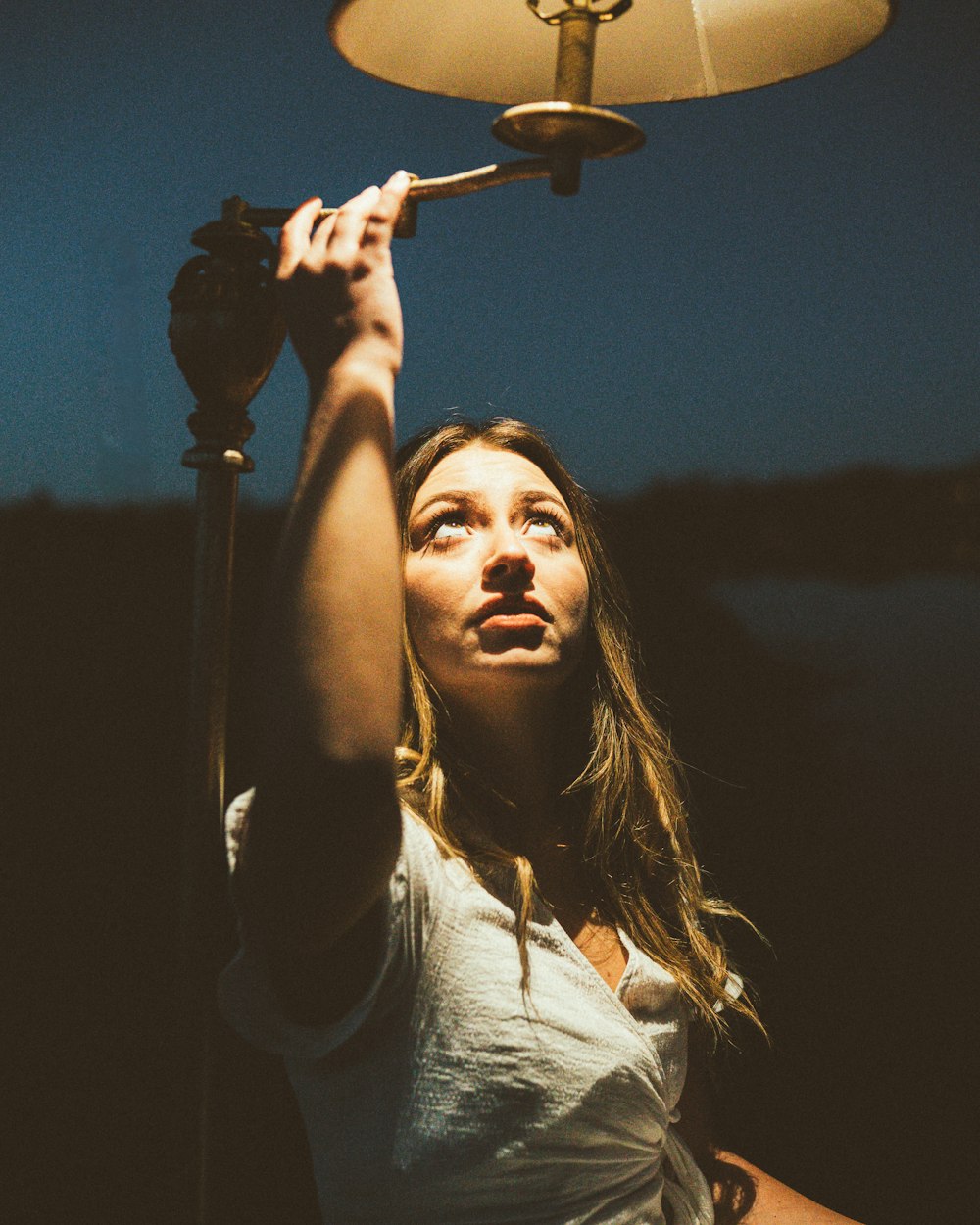 a woman holding a lamp up to the sky