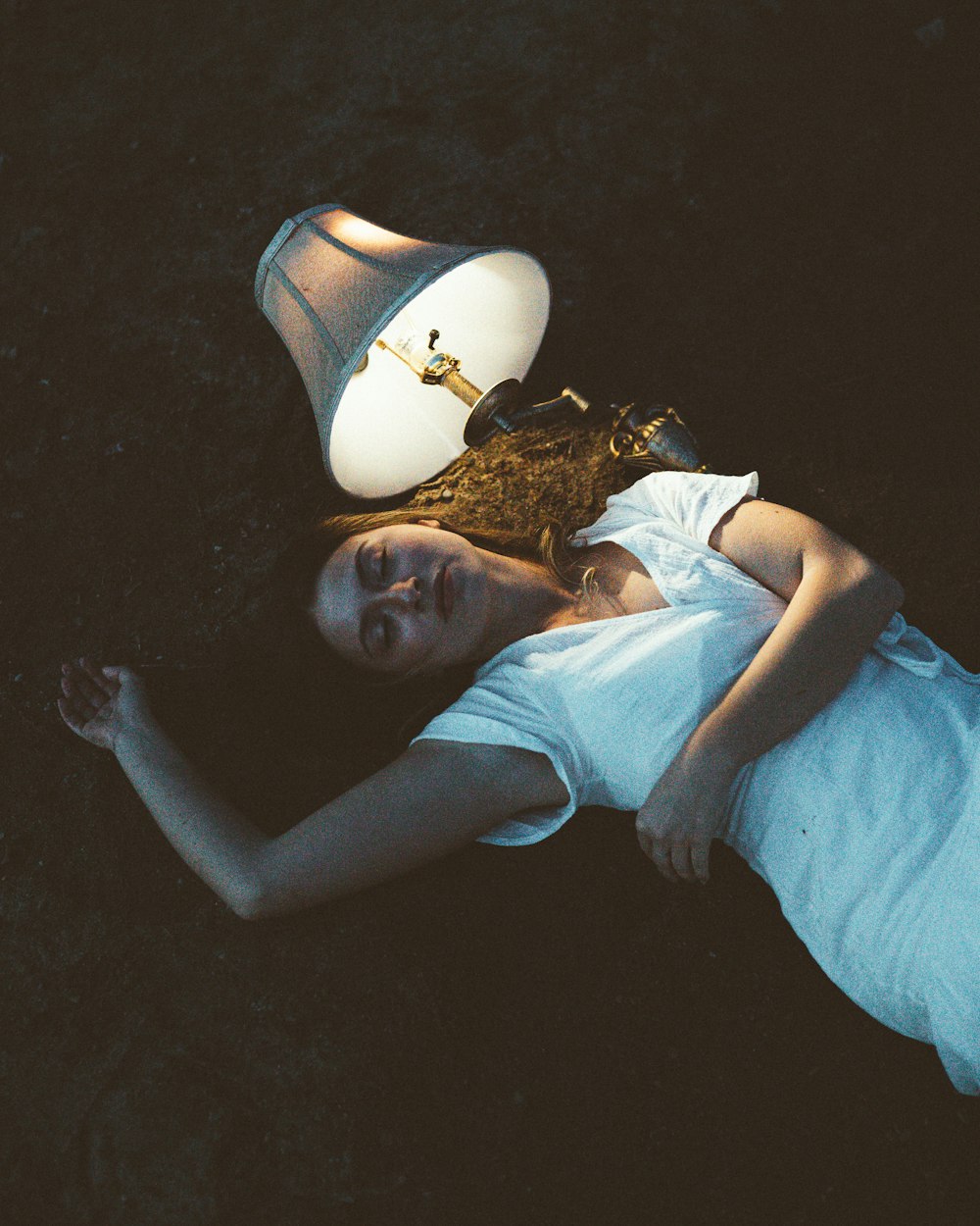 a woman laying on the ground next to a lamp