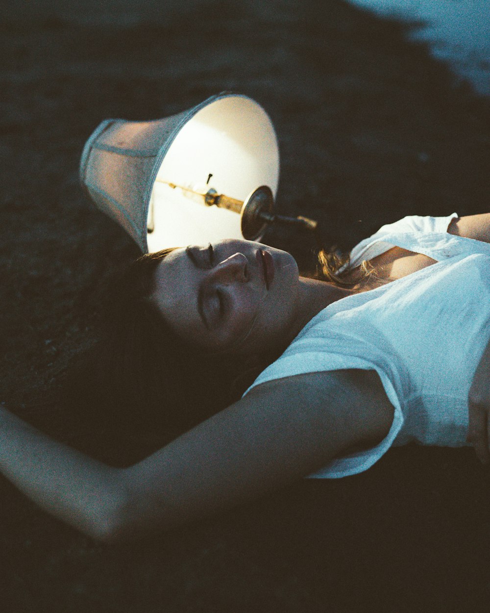 a woman laying on the ground with a lamp on her head