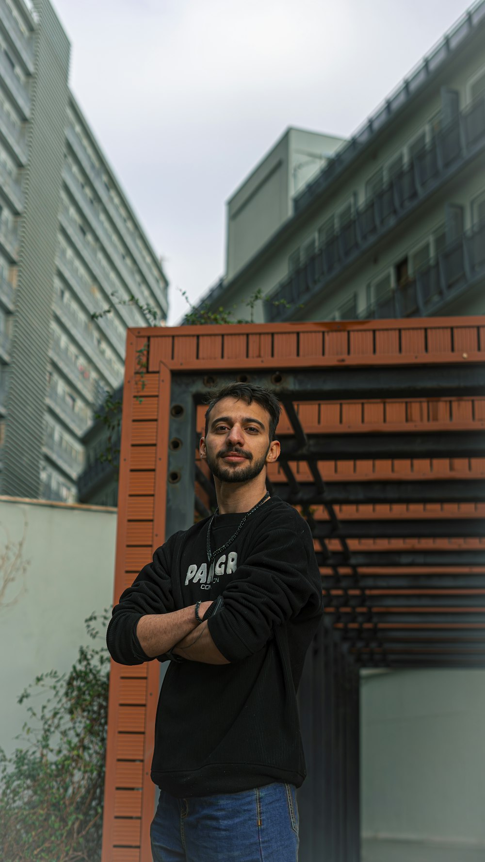 a man standing in front of a building with his arms crossed