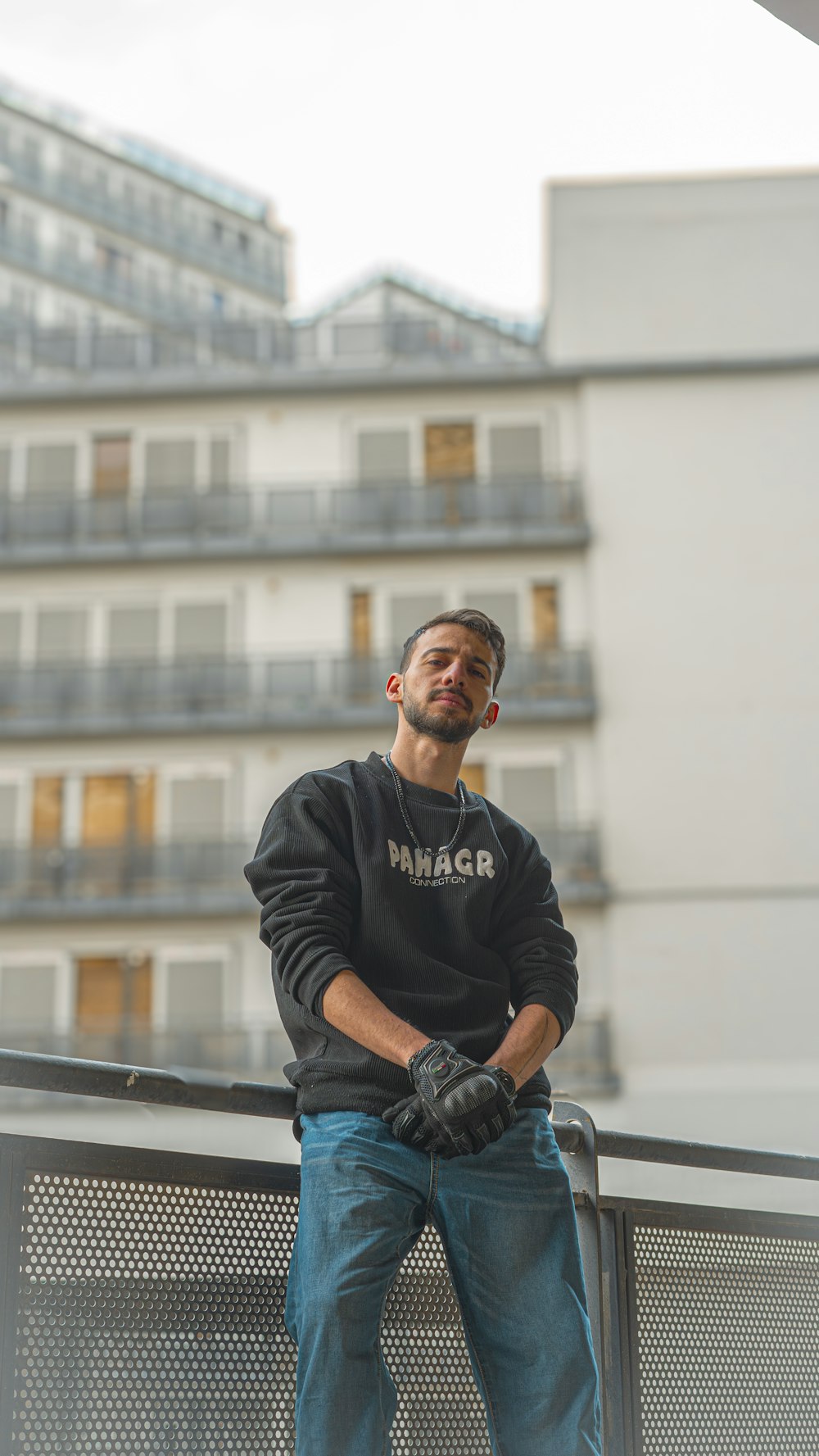 a man leaning on a fence with his arms crossed