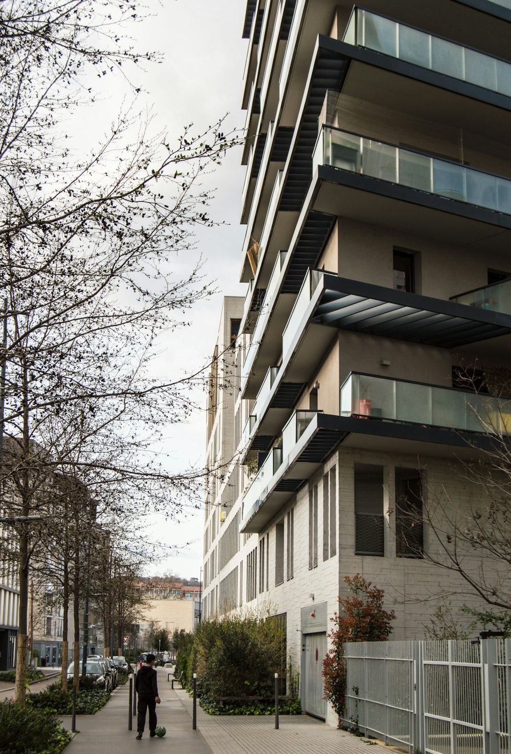 a man walking down a sidewalk next to a tall building