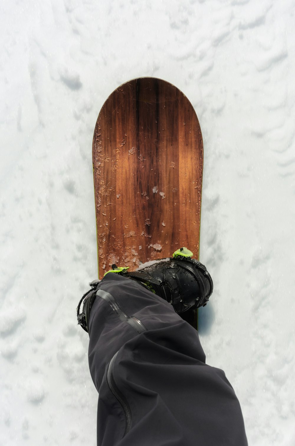 a person's feet in the snow next to a snowboard