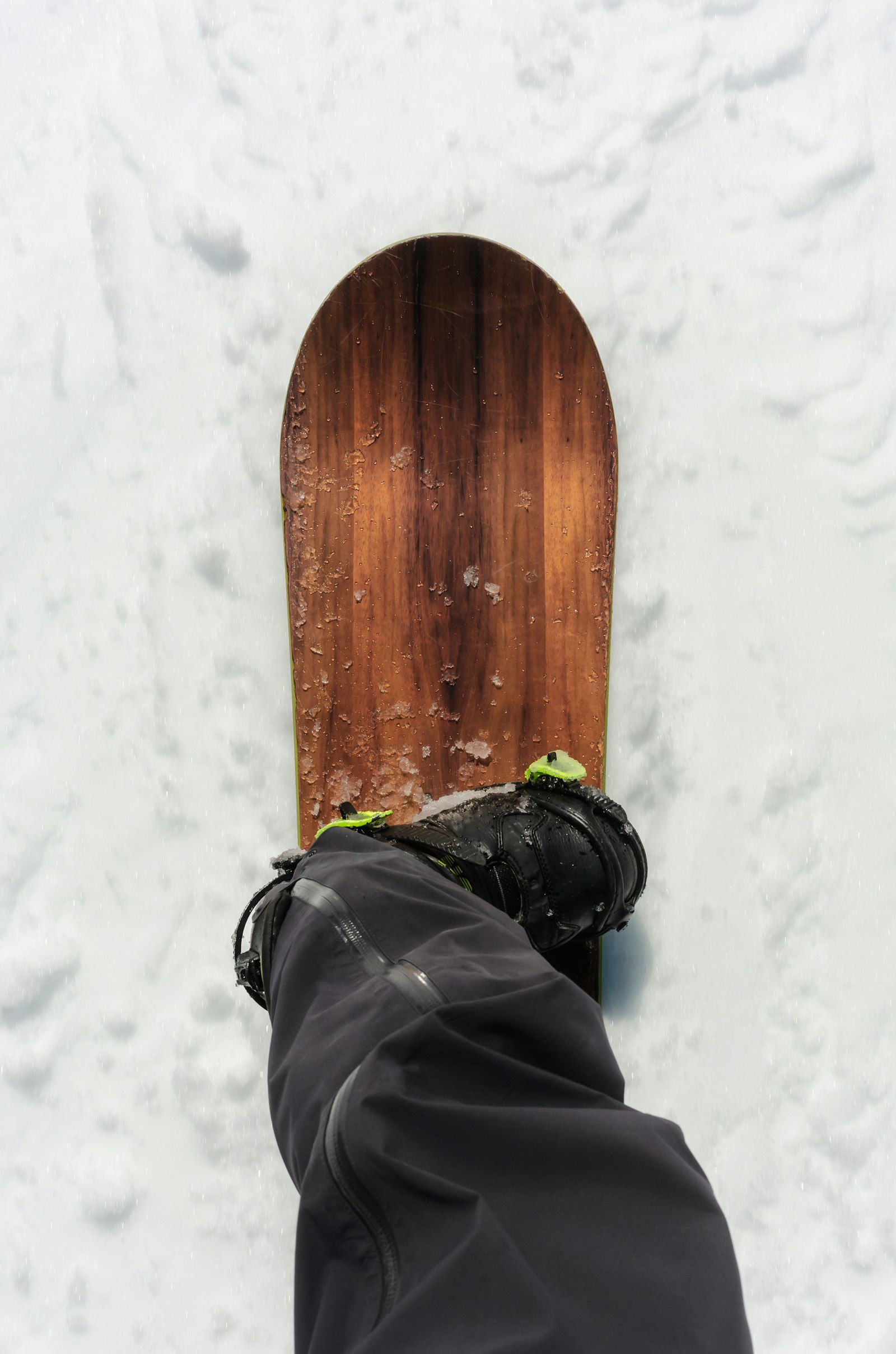 A snowboard boot strapped into a binding on a board