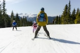 a man and two children skiing on a mountain