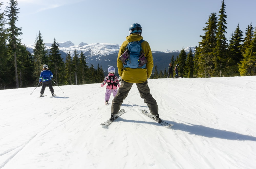 un uomo e due bambini che sciano su una montagna