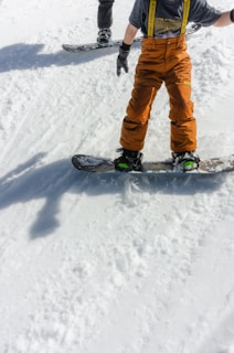 a young boy riding a snowboard down a snow covered slope