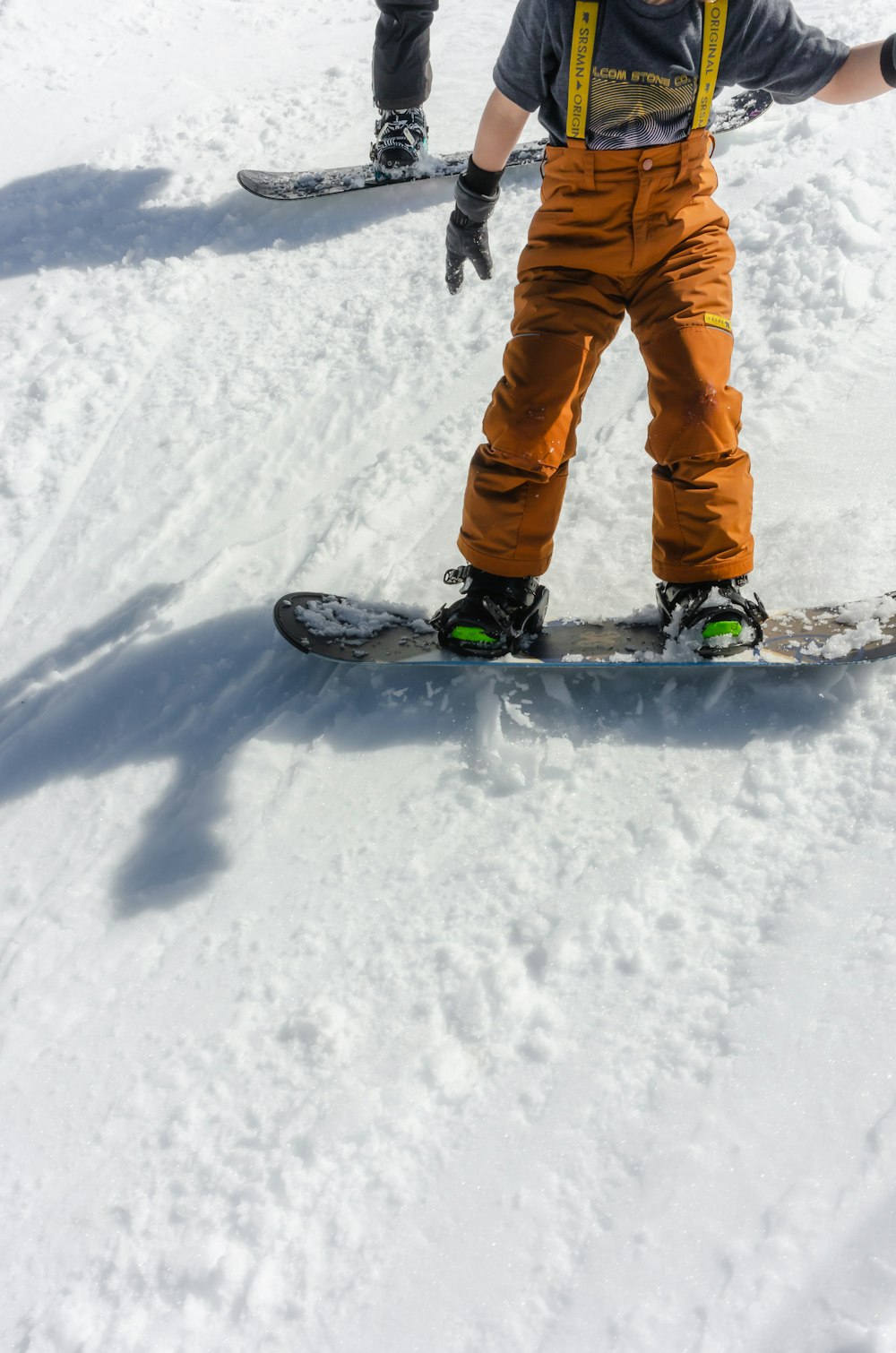 a young boy riding a snowboard down a snow covered slope