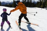 a woman teaching a child how to ski