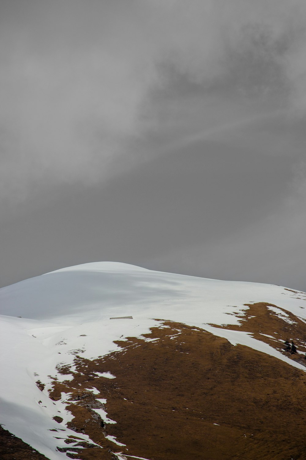 a hill covered in snow under a cloudy sky