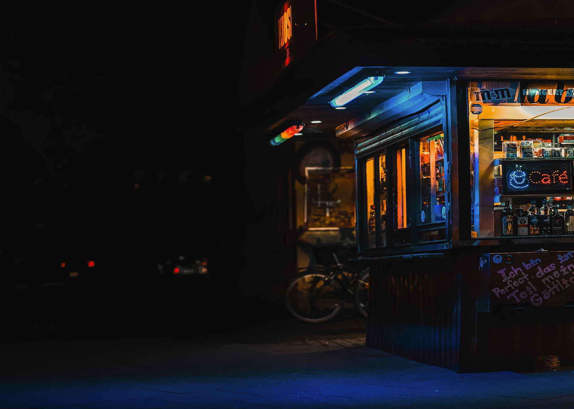 a dark street with a lit up kiosk at night