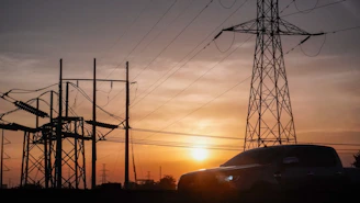 a car is parked in front of power lines at sunset