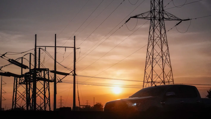 a car is parked in front of power lines at sunset