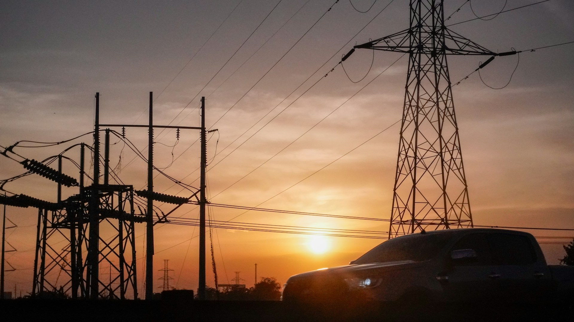 a car is parked in front of power lines at sunset