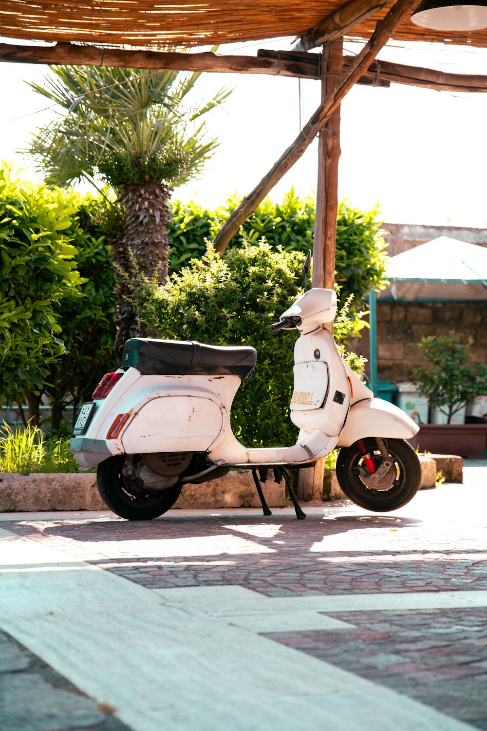 uma scooter branca estacionada sob uma estrutura de madeira