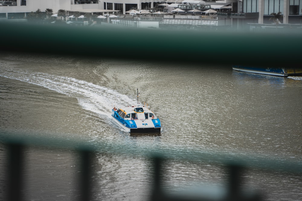 a blue and white boat traveling through a body of water