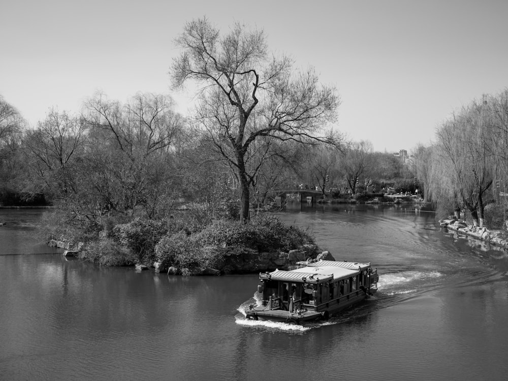 a boat traveling down a river next to a forest