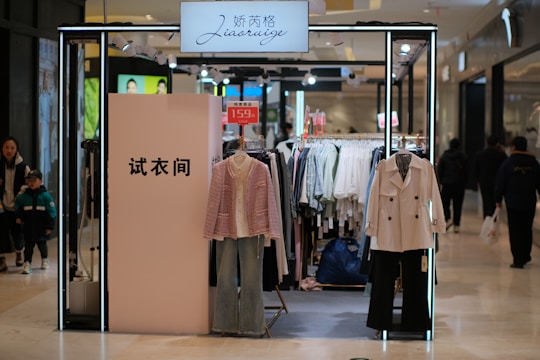 a clothing store with clothes on display and people walking by
