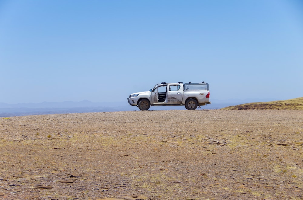 a pick up truck parked on the side of a dirt road