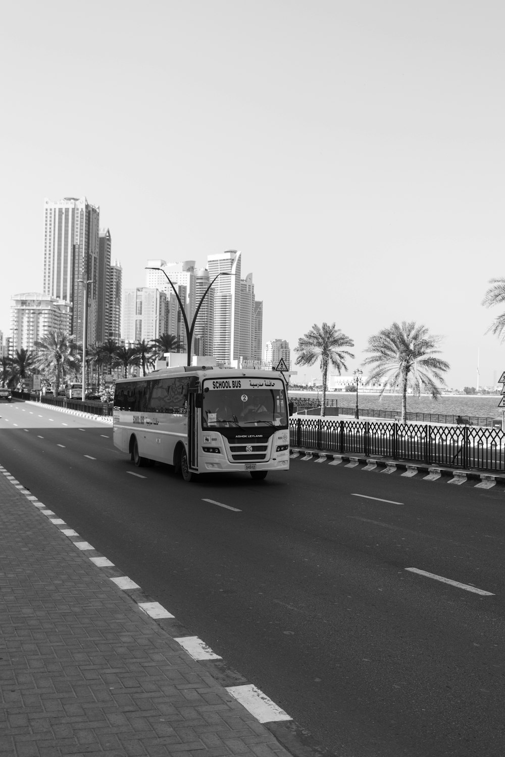 a white bus driving down a street next to tall buildings