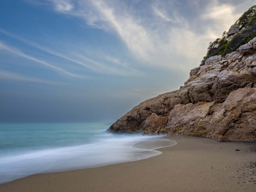 a sandy beach next to the ocean under a cloudy sky