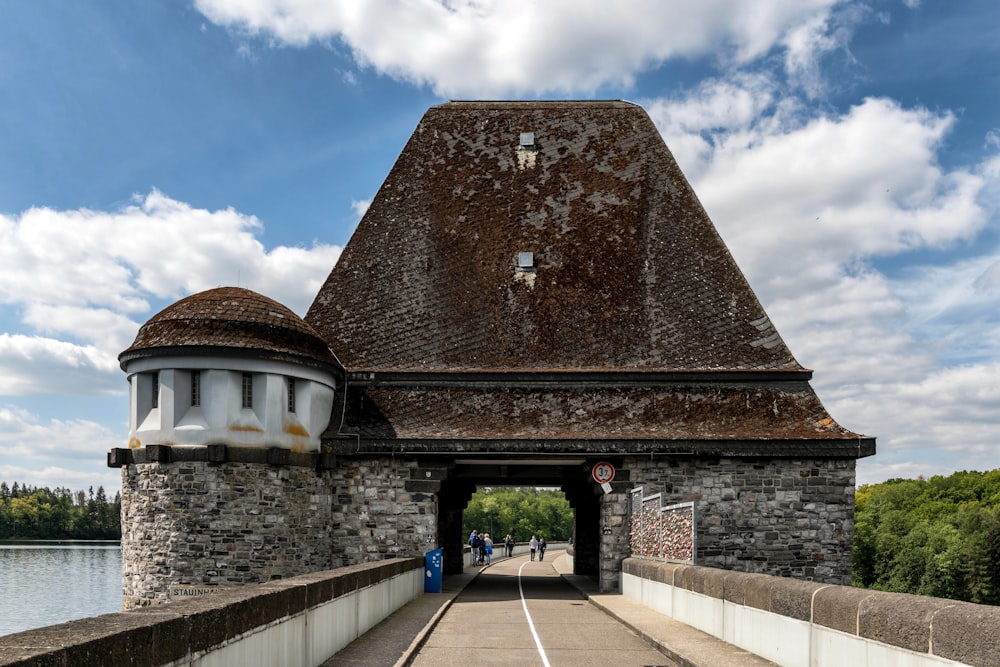 a stone building with a brown roof next to a body of water