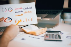 a person holding a piece of paper over a laptop