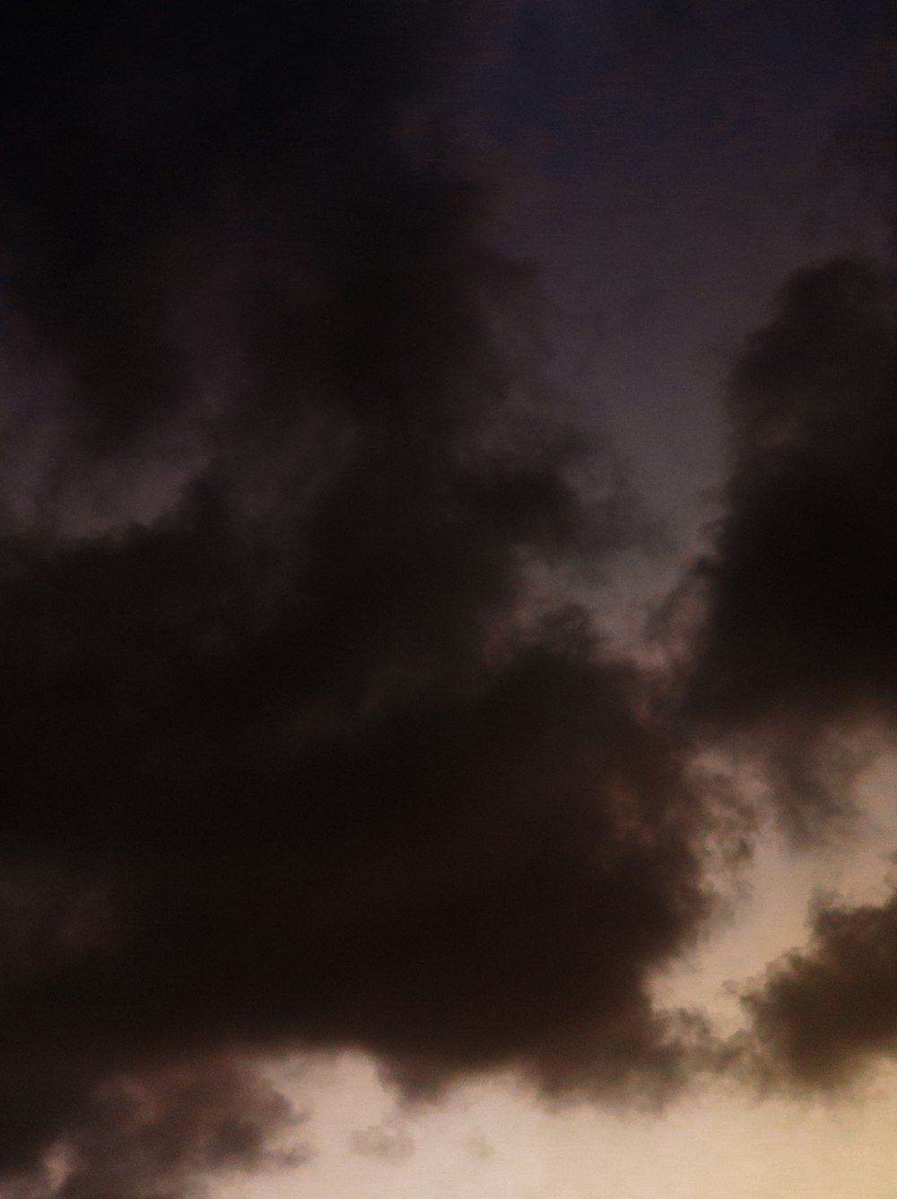 a plane flying through a cloudy sky at sunset