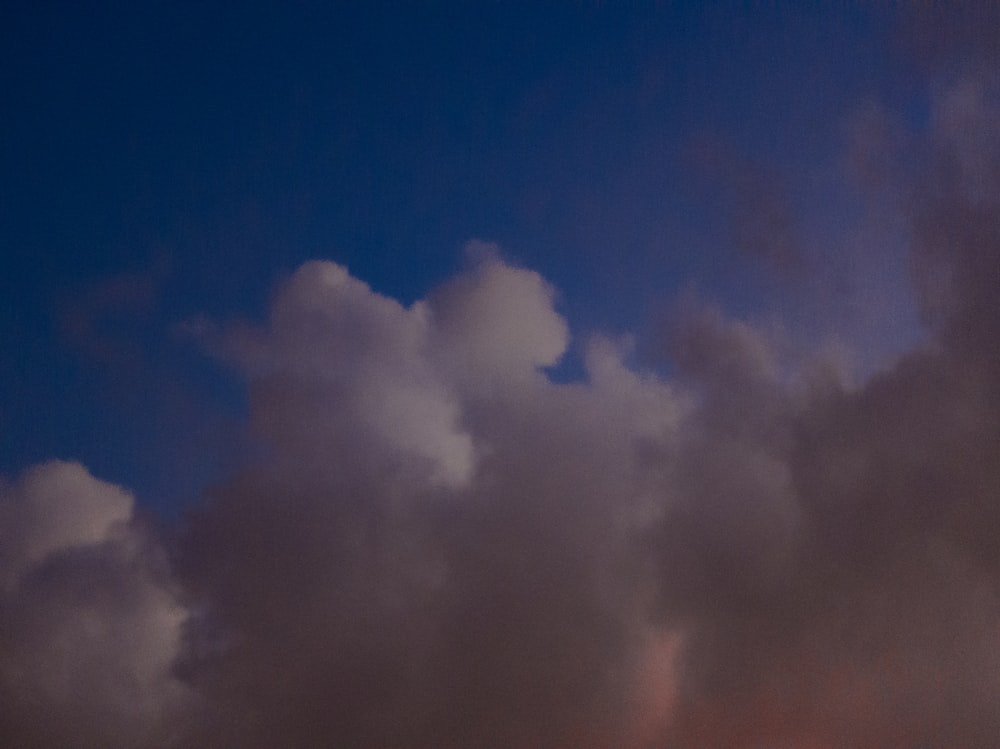 a plane flying through a cloudy blue sky